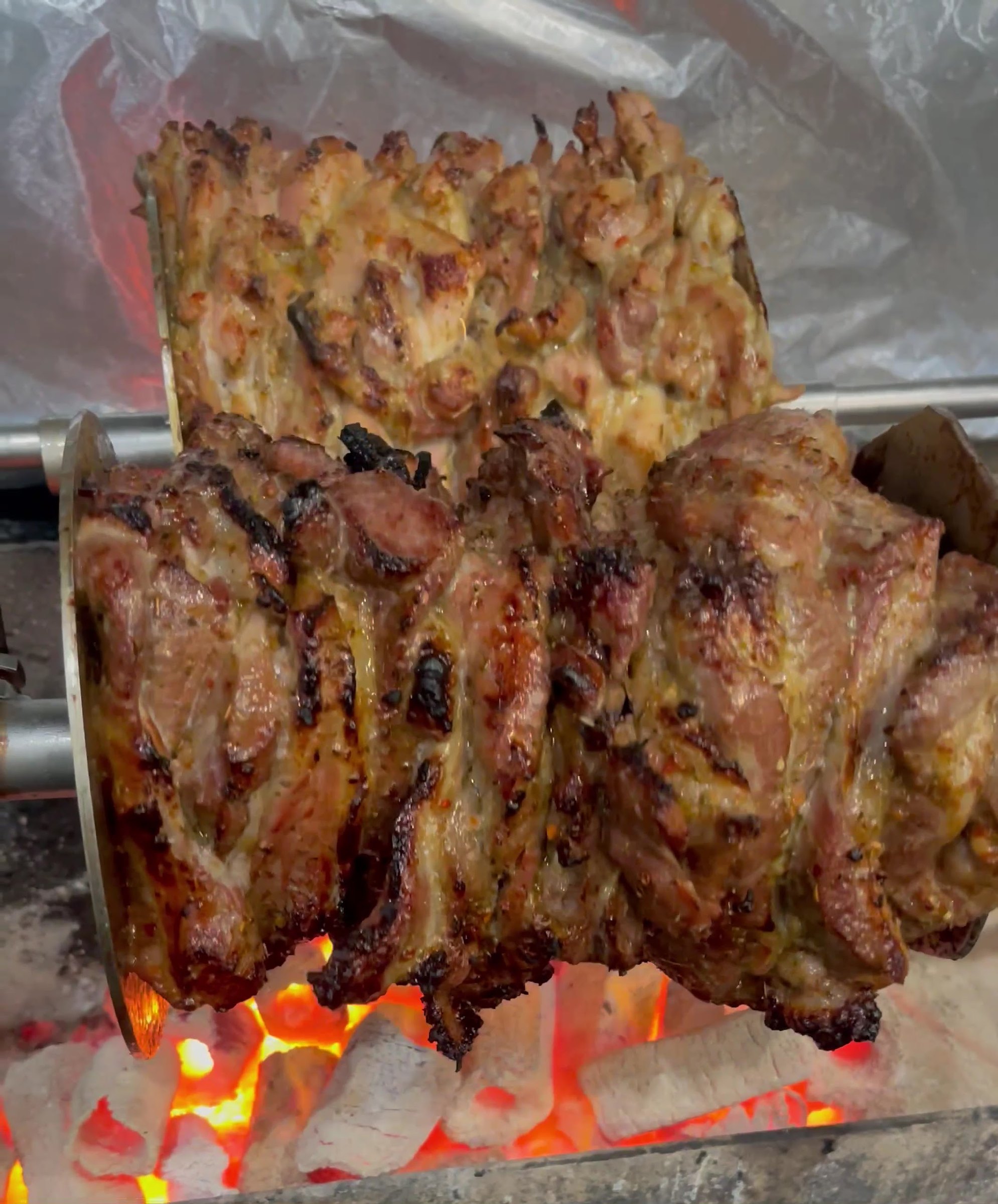 Lamb and chicken gyros turning over glowing charcoal